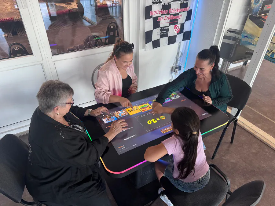 Vier Gäste spielen gemeinsam am digitalen Spieltisch in der Indoor Kartbahn Kassel